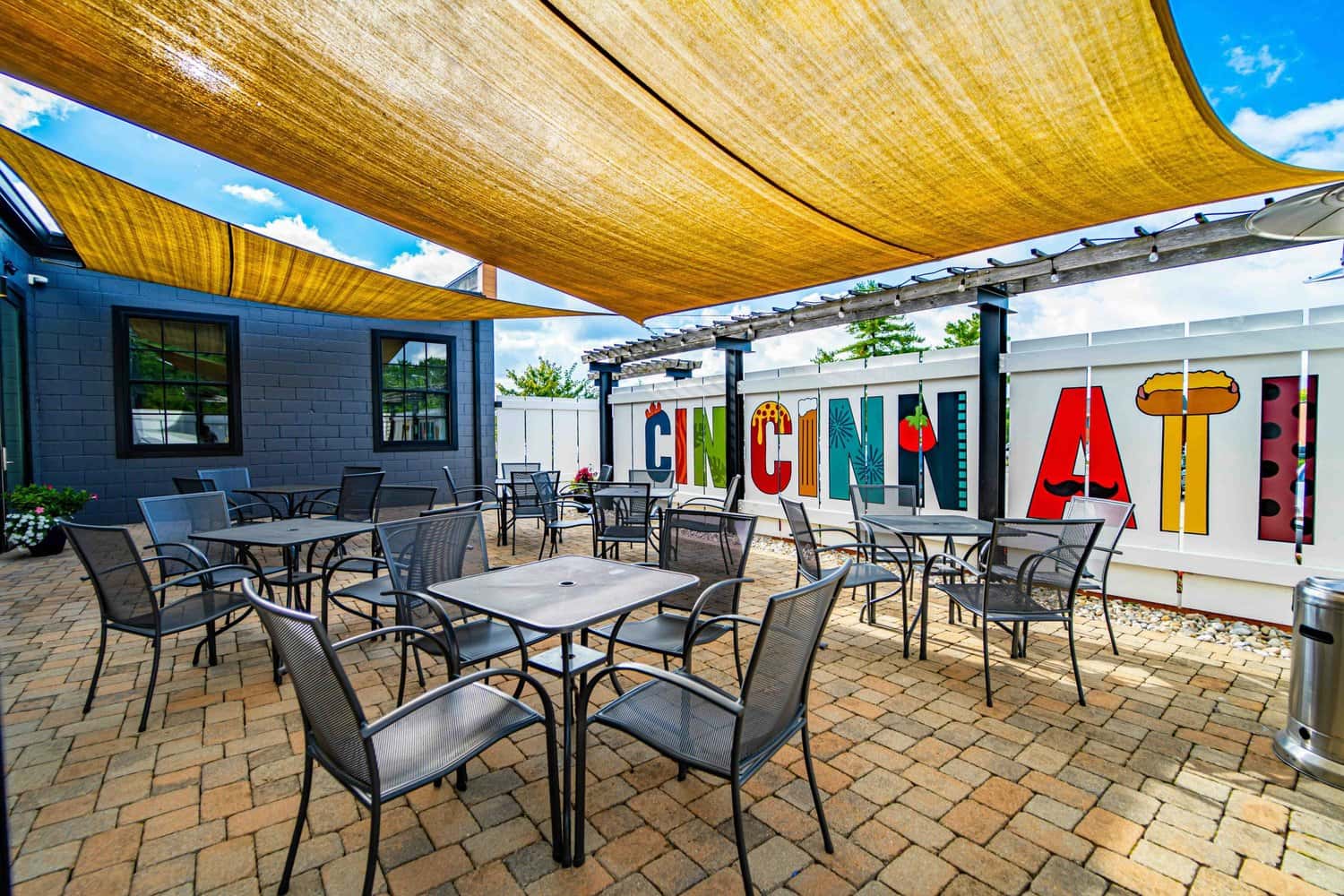 The adjoining patio with tables, shade sails, and the Cincinnati mural